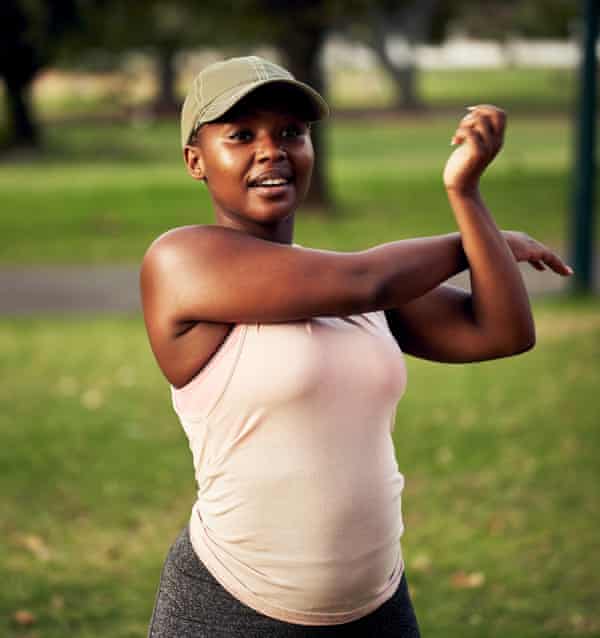 A young woman stretches in a park.