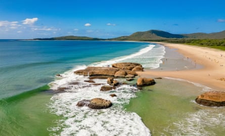 Picturesque view of beach and clear water with treed hills in the background