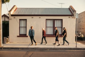 Four men walking past a house
