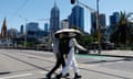 Two people in Melbourne sheltering under an umbrella from the sun