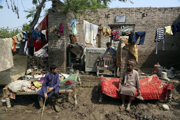 Egy család megpihen, miután kihozta holmiját árvízkárosult otthonából a pakisztáni Charsaddában.