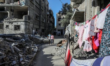 Palestinian children walk among the rubble of buildings destroyed by Israeli attacks.