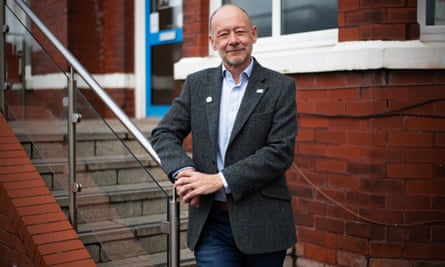 Dr David Unwin, in a suit jacket, standing on stairs and smiling