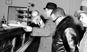 Assistant district attorney David Blatt, left, and detectives stand by as Nicky Barnes is booked at Bronx police station.