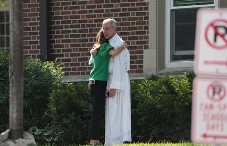 A clergyman hugs a woman outside of a building