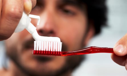 Một người đàn ông bôi kem đánh răng vào bàn chải đánh răng