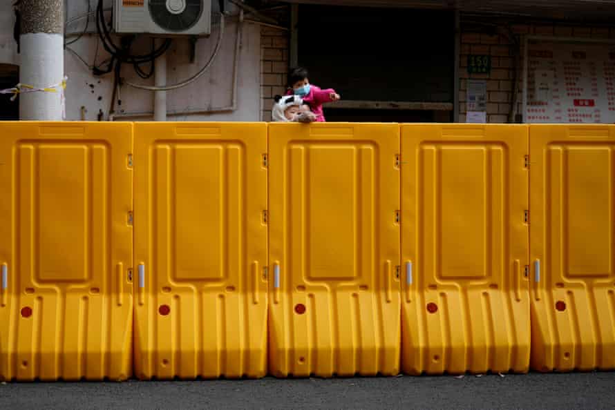 People peer over a barrier of an area under lockdown in Shanghai on 26 March.