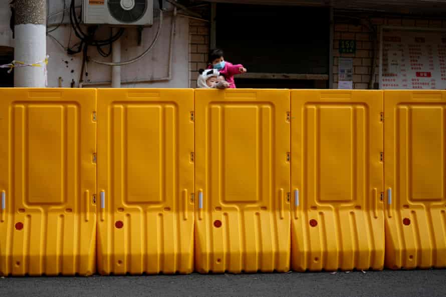 Les gens regardent par-dessus une barrière d'une zone sous verrouillage à Shanghai le 26 mars.