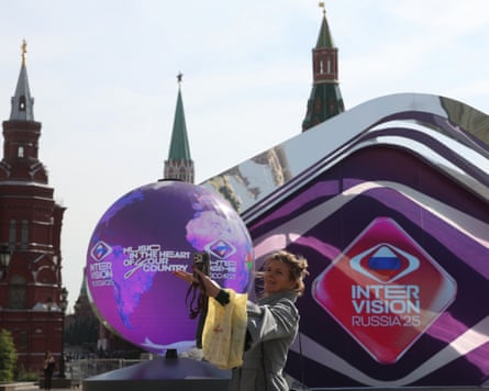 A woman takes a selfie in front of a shiny silver monument.