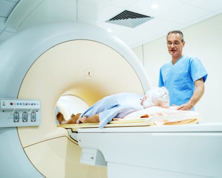 A patient about to receive a CAT scan talks to a doctor.