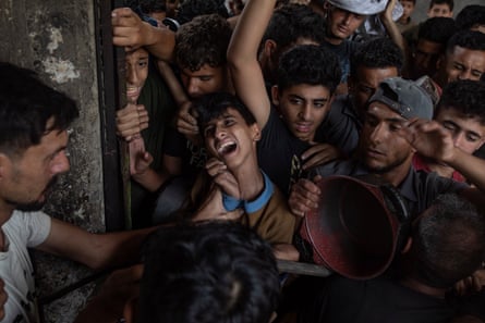 Palestinians gather outside a charity kitchen in Gaza City to receive limited food rations, 18 May 2025.