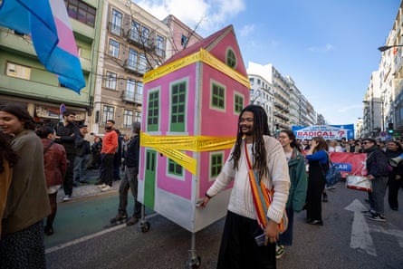 Protesters march on the street while carrying a small house during a housing demonstration, January 2024.