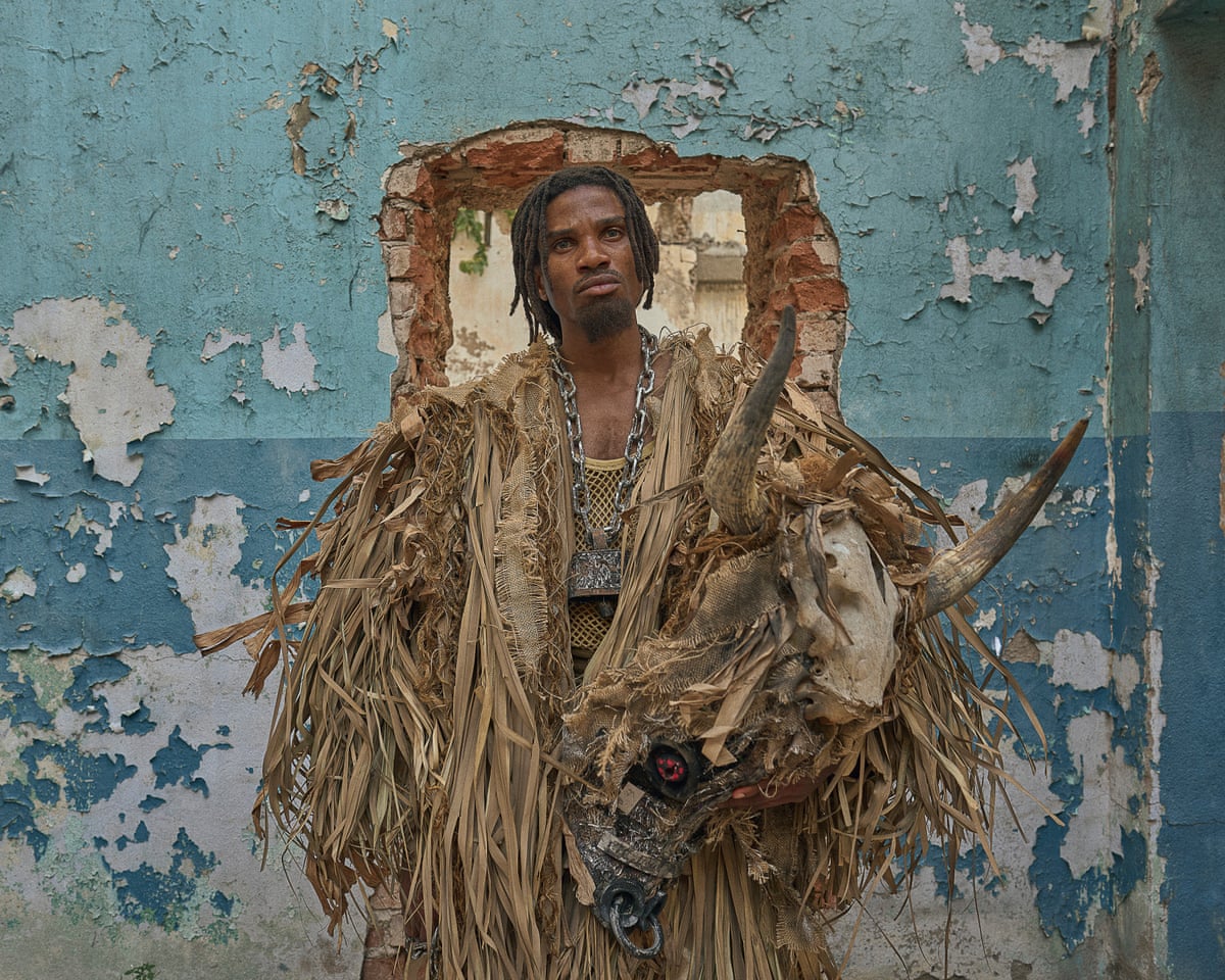 Sheldon East as Cudjoe East wearing robes and the head of a tusked animal