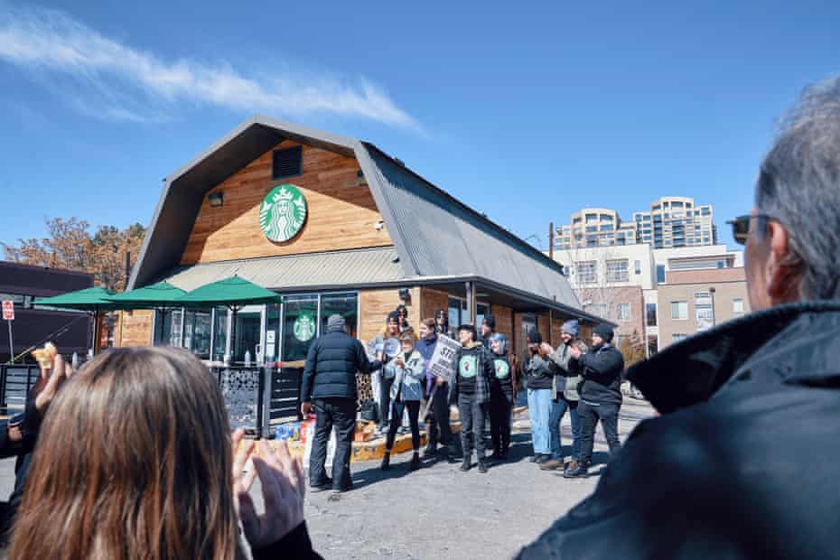 people gather, smiling, outside a starbucks