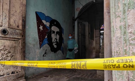 A Covid-19 support personnel walks past a mural depicting revolutionary leader Ernesto Che Guevara in a restricted area after cases of coronavirus were detected in Havana. Cuban authorities announced new measures to control a surge of Covid-19 with increased penalties for people who do not comply with health regulations and campaigns to persuade the population to take the risk more seriously.