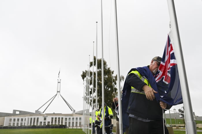 Workers prepare Australian flags to fly at half mast outside Parliament House in Canberra.