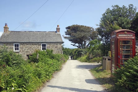 A rural scene with a stone house and red British telephone box along a narrow path under a blue sky
