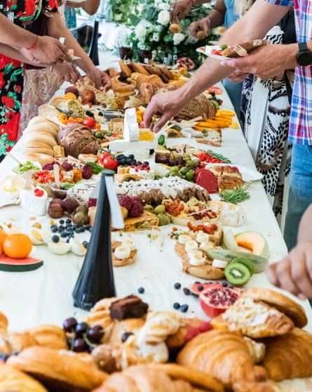 long table of food with people reaching to fill plates