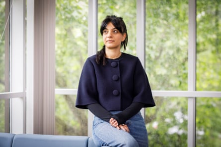 Pavan Dhaliwal sits in an office in front of a wall of glass windows