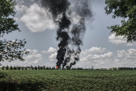 Several large plumes of dark smoke pictures from across a green field