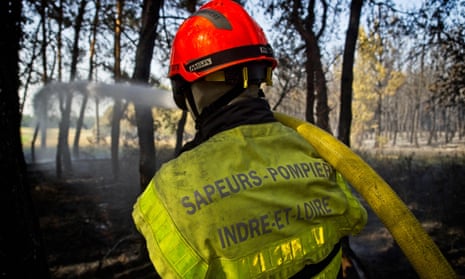 A firefighter sprays water to extinguish a blaze in a forest in Genille, central France.