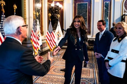 a woman smiles as she extends her hand to shake a man’s hand