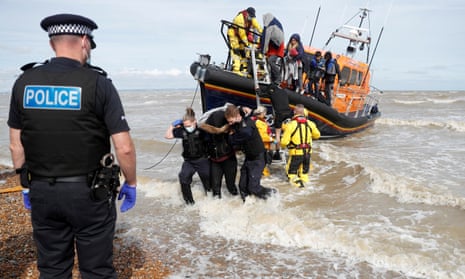 A RNLI boat, with migrants onboard, is met by border force officers and police at Dungeness, Britain.