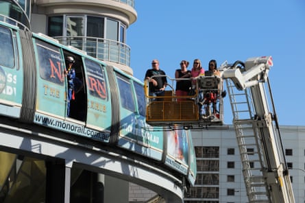 A cherrypicker moves several passengers away from the monorail, which has broken down with its doors open and rescue personnel about