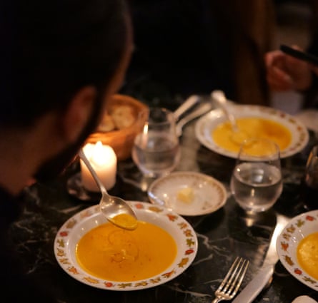 People eating soup at a candlelit table.