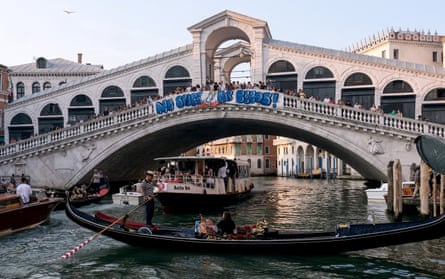 A banner on the Rialto bridge reading No Space for Bezos, with gondolier underneath