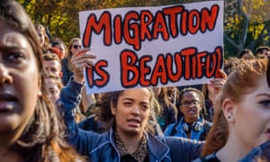 A student holding a 'Migration is beautiful' sign at an anti-Trump rally in New York
