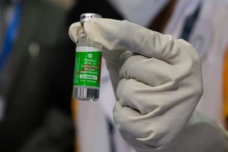A gloved hand holding a vial of Covid vaccine