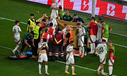 Players and stewards hold up sheeting to cover Barnabas Varga as he receives treatment after a collision.