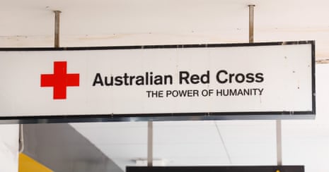 A white sign for the Australian Red Cross hangs from a roof.