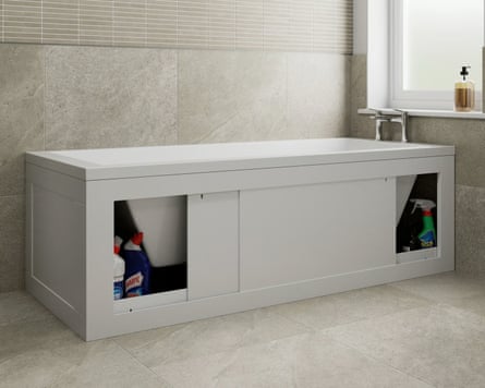 A white bath in a stone coloured bathroom. The bath panel is a sliding door and it’s open to reveal storage space for cleaning products