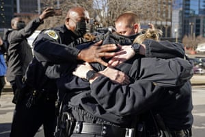 Police Chief John Drake, left, joins a group of police officers as they embrace after speaking at a news conference on Sunday.