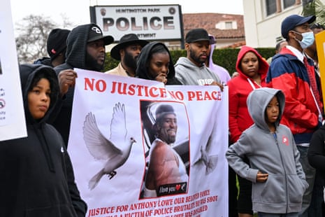 people protest after lowe’s death - sign says ‘no justice no peace’ with picture of Lowe