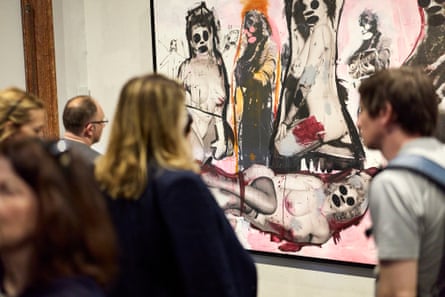 People look at a mixed-media artwork featuring naked woman with black blobs of paint over their eyes and mouths, plus scribbles and drawings across the canvas