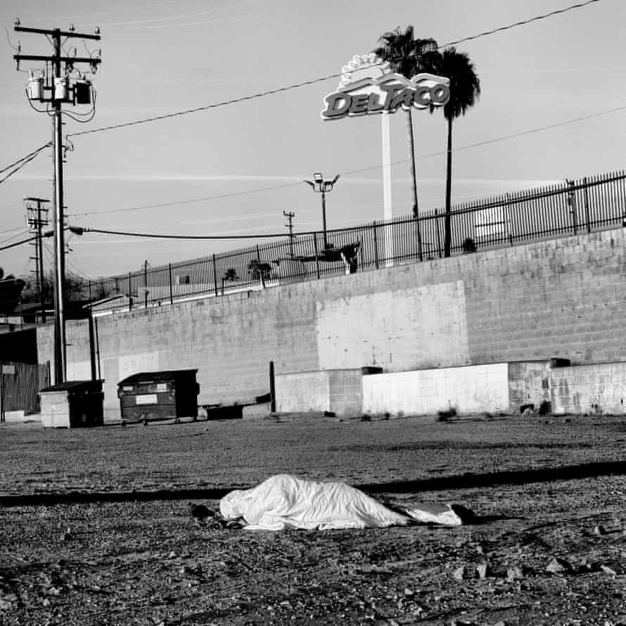 USA. Barstow, California. 2020. A man sleeps in an empty lot.