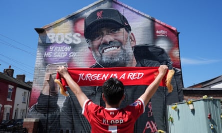 A Liverpool fan salutes a Klopp mural at Anfield.
