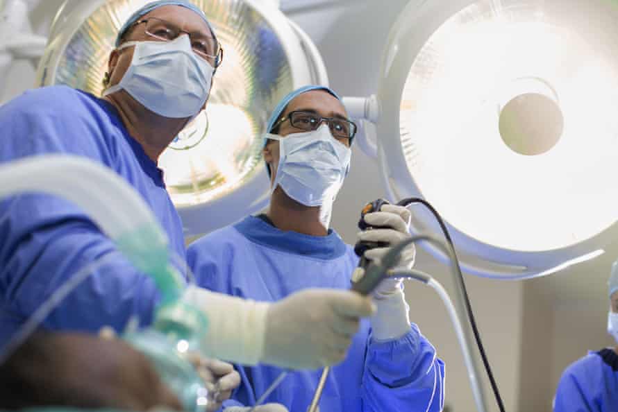 Surgeons holding laparoscopy equipment in an operating theatre 
