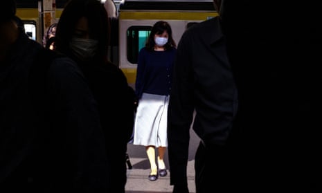 People wearing face masks get off a train at Shinjuku Station in Tokyo 