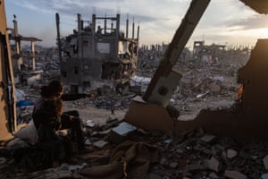 People watch the sunset from the rubble of a destroyed house