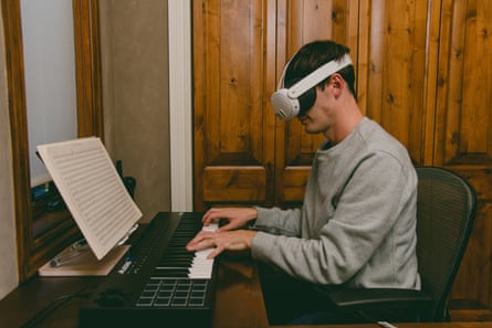 Composer Ed Newton-Rex plays a keyboard piano while wearing a virtual reality headset at home in Palo Alto, California.