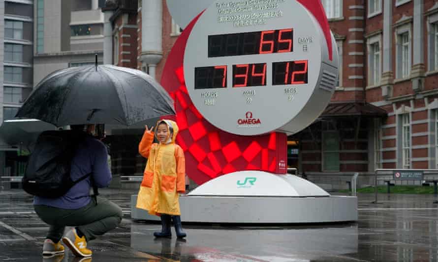 A boy poses in front of an Olympic countdown clock in Tokyo indicating the remaining days until the opening ceremony for the Games.