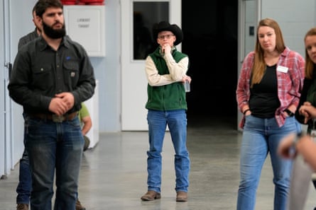 People standing, one in green vest