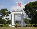 Peace Arch at the USA-Canada border with American and Canadian flags flying, two people standing beneath
