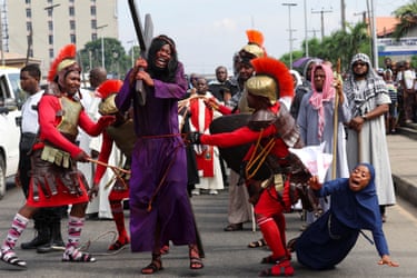 Image 13: An actor carries the cross and is pushed by Roman soldiers. A woman falls and cries. They are all part of the re-enactment