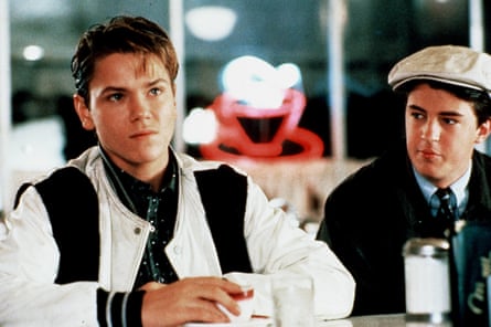 A boy in a baseball jacket and a boy in a black jacket with a flat cap