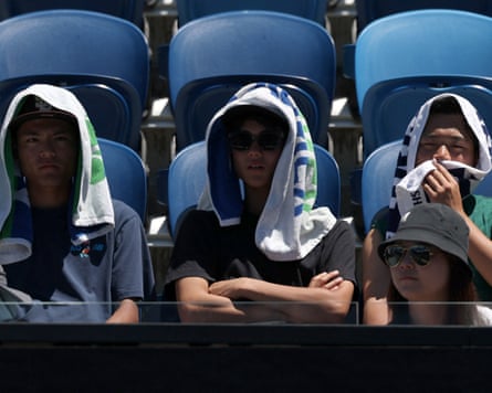 Spectators use towels to hide from the heat while watching tennis at Melbourne Park for the Australian Open
